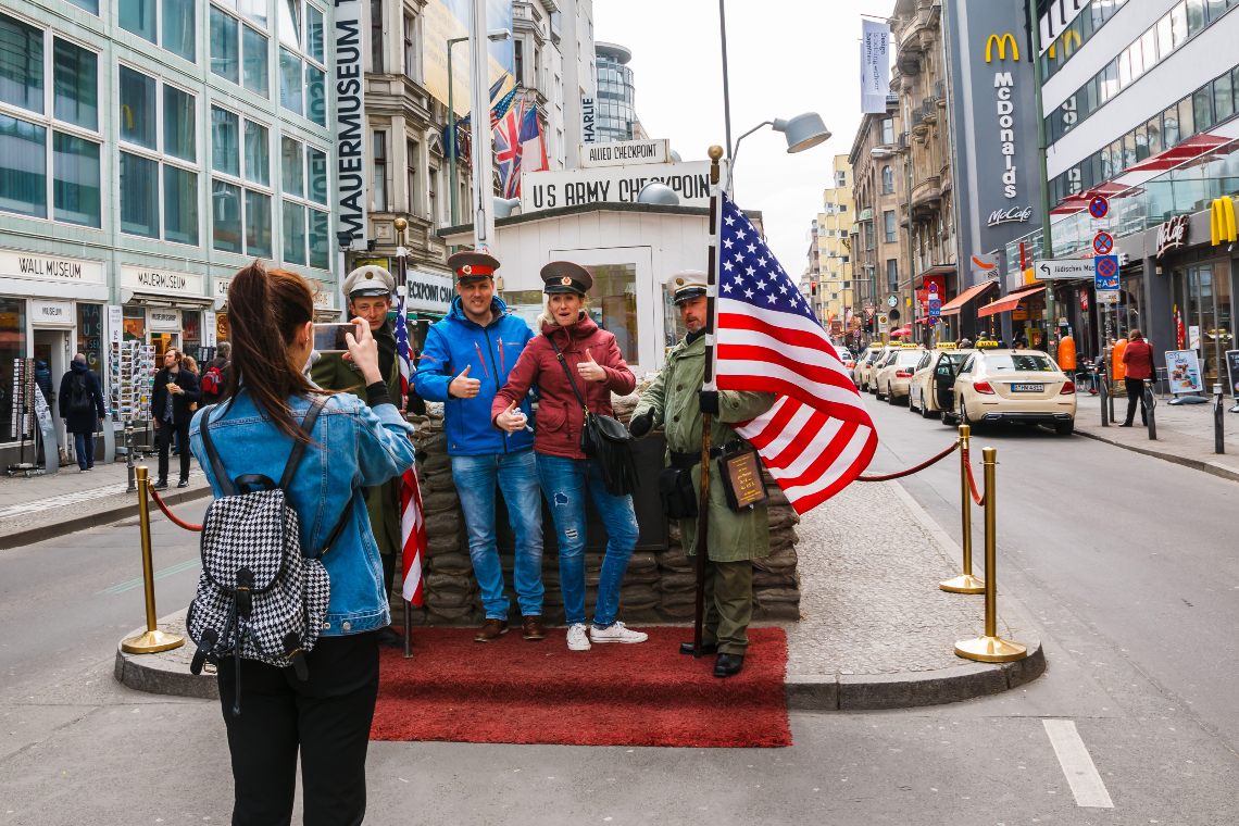 Travellers posing for a photo with guards at Checkpoint Charlie
